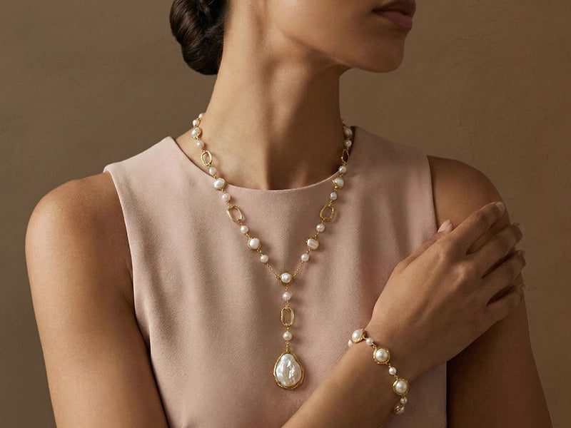 Woman wearing a pearl necklace and bracelet against a beige background