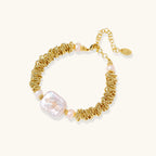 18k gold-plated bracelet with textured wave segments, baroque pearl centerpiece, and round freshwater pearls on cream background