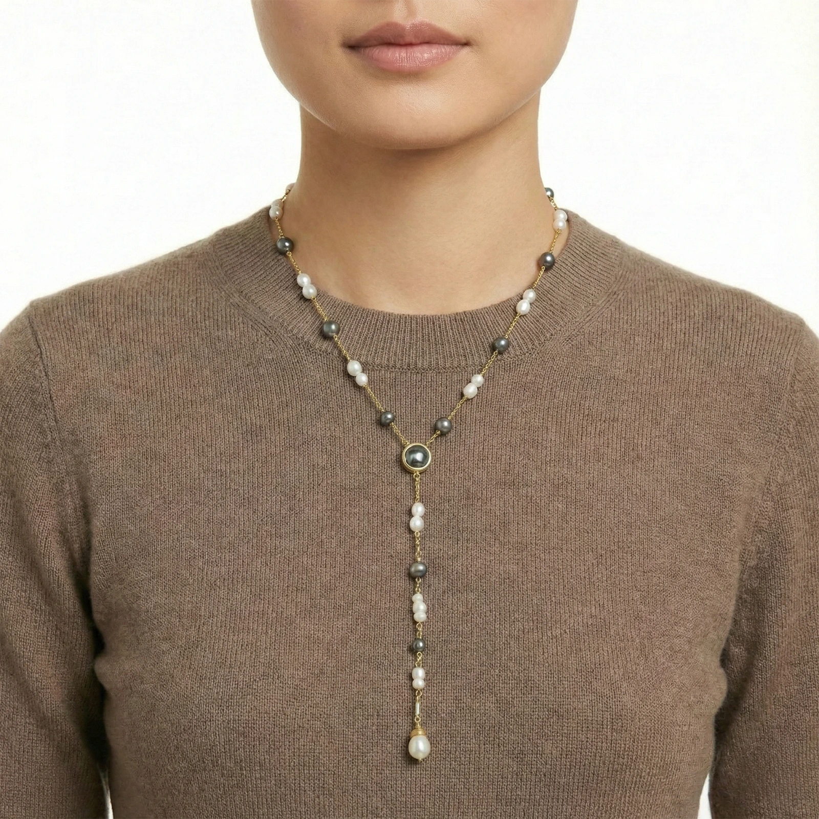 Person wearing a long beaded necklace with a neutral background